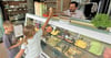 Dashmir Miniri vom „Eiscafé Orient“ reicht Snickers-Eis an Bennet und Élise über die Ladentheke.