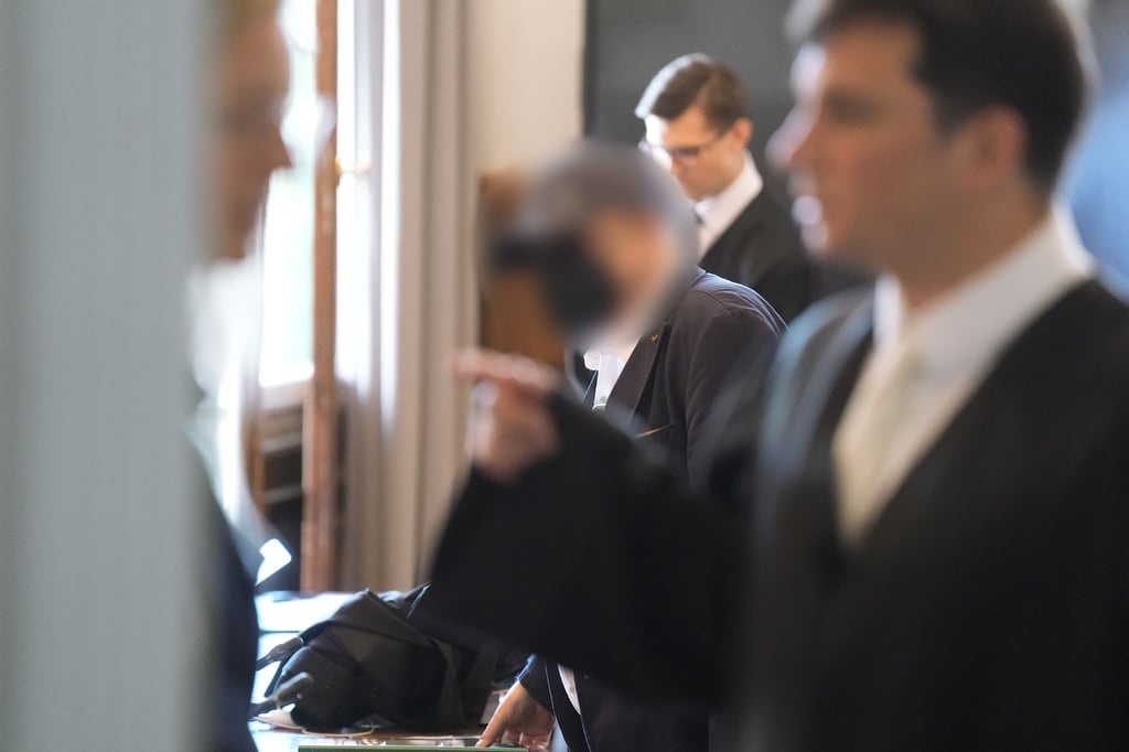 Einer der Angeklagten (M) betritt den Gerichtssaal in Hamburg.