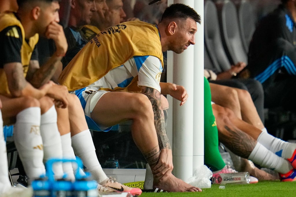 Lionel Messi fasst sich an den geschwollenen verletzten rechten Knöchel.