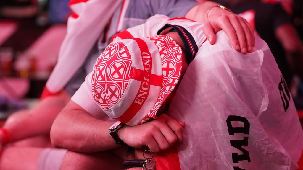 Ein England-Fan kauert traurig in eine Flagge gehüllt.