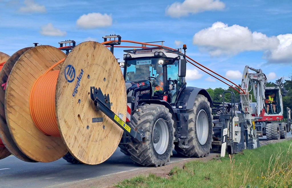 Mit einer speziellen Fräse werden die Leitungen in die Erde verlegt, anschließend wird das Straßenbankett wieder verdichtet.
