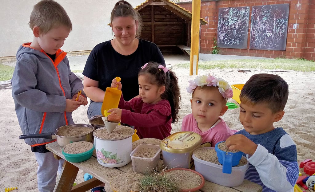 Erzieherin Maria Mattick beaufsichtigt Kinder, die im großen Sandkastenbereich spielen.