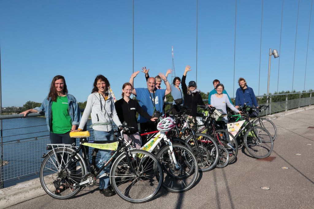 Das Floß wird von Fahrradfahrern an Land begleitet.