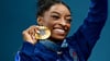 Simone Biles zeigt stolz ihre sechste olympische Goldmedaille.