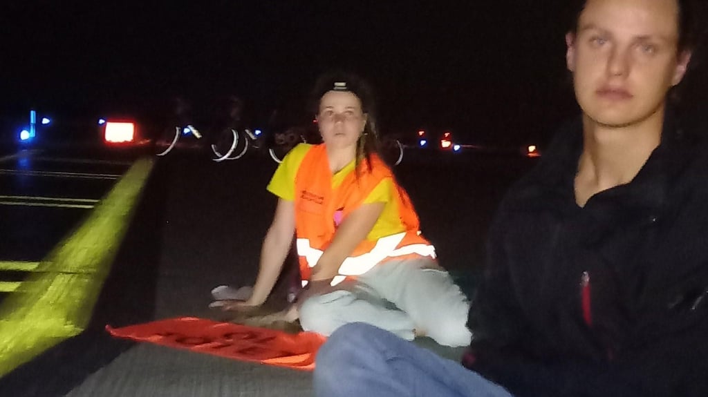 Mit den Händen haben sich Klimakleber der Letzten Generation auf dem Rollfeld des Flughafens Leipzig-Halle festgeklebt.