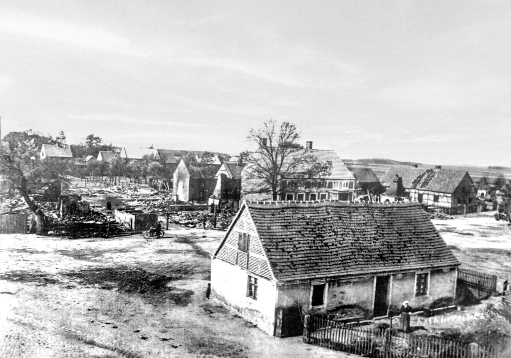 Das halbe Dorf war 1907 niedergebrannt. Das Foto zeigt die Ortsmitte. Im Hintergrund Reste von abgebrannten Gebäuden.