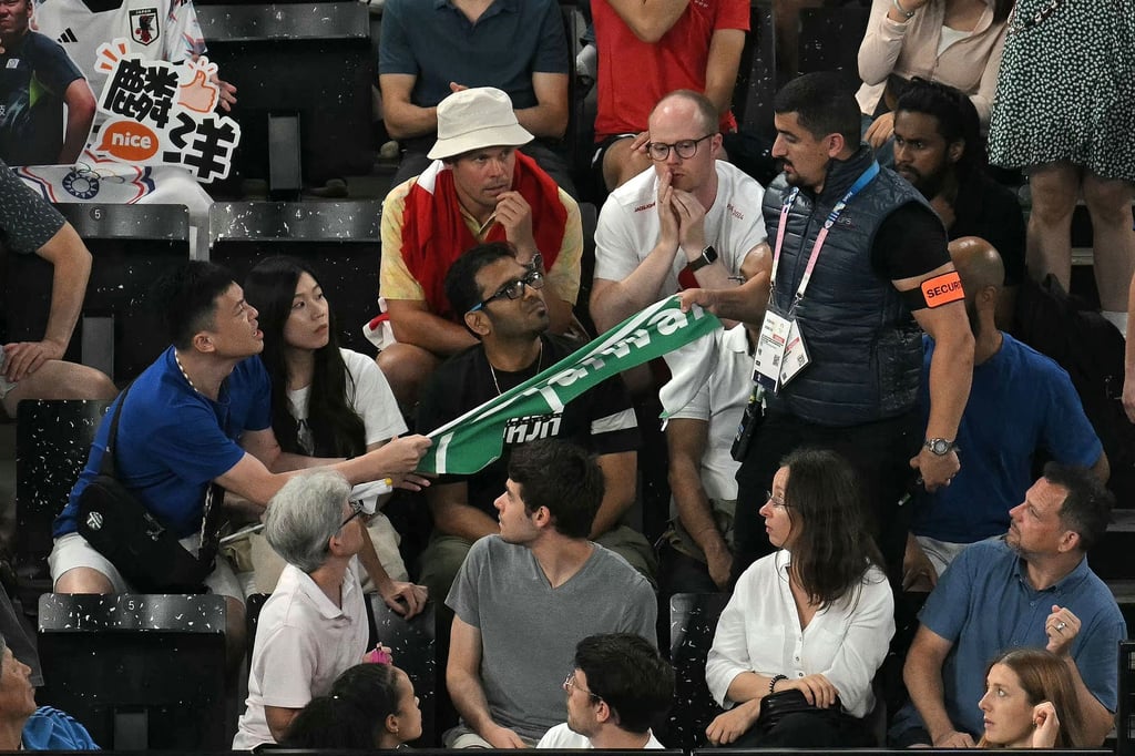 Ein Sicherheitsmann entfernt ein Transparent mit der Aufschrift "Taiwan" beim Badminton.