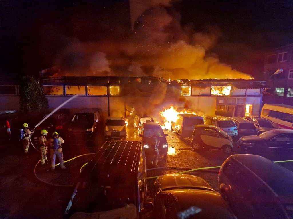 Einsatzkräfte der Feuerwehr löschen den Brand in einer Autowerkstatt in Alt-Hohenschönhausen in Berlin.