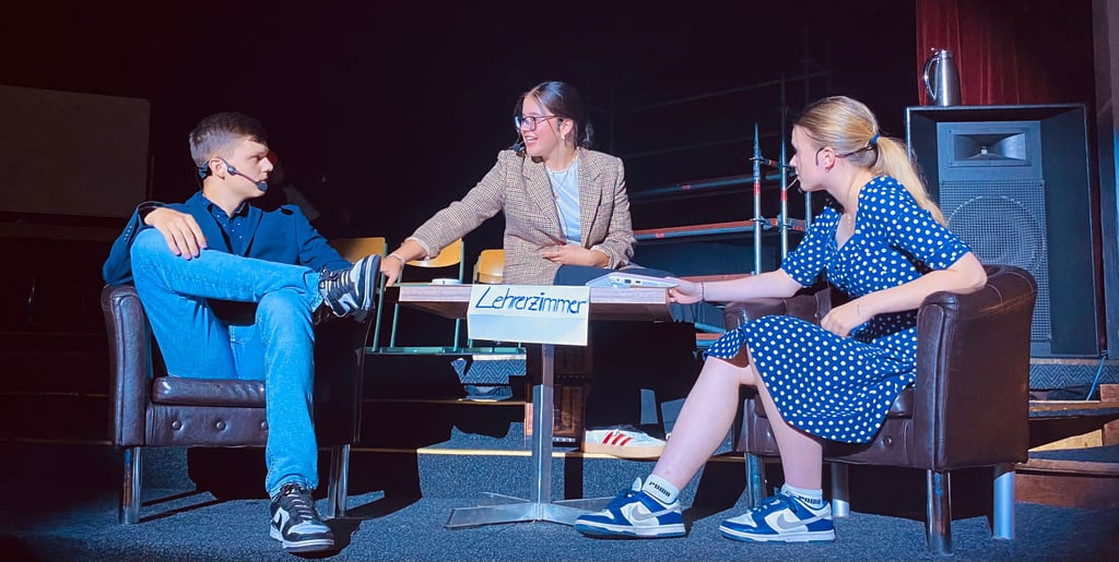 Beim Theaterstück „270 Tage“: Lehrer Flöcke (Luis Kleinau) im Gespräch mit Ehefrau (r., Paulina Mühe) und Referendarin Frau Schneider (Malou Wehling).