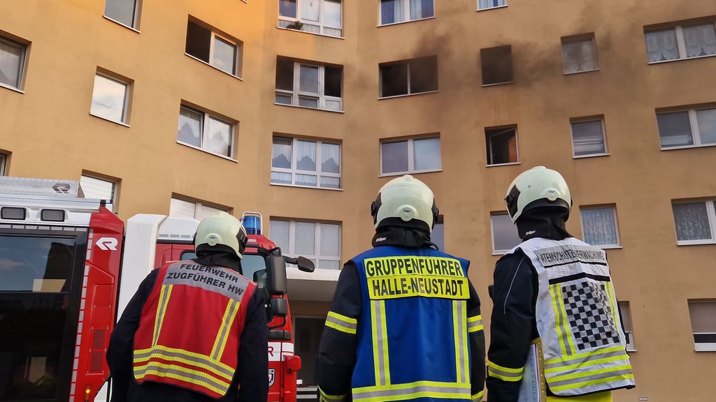 Einsatzkräfte der Feuerwehr Halle vor dem Wohnblock in Neustadt.
