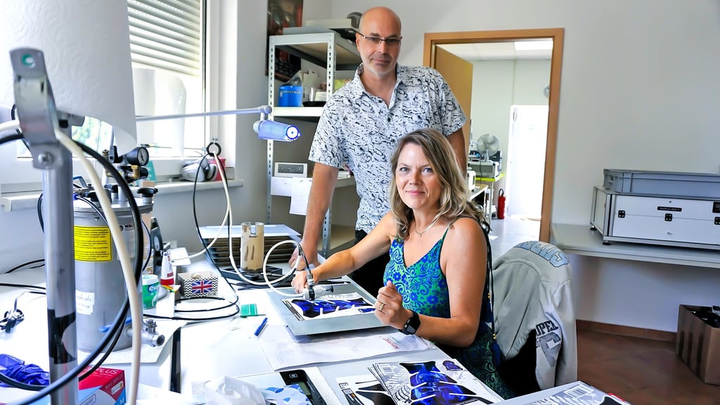 Hendrik und Claudia Matz an dem Arbeitsplatz, wo der Kunststoff von Hand auf die Motive aufgebracht wird.