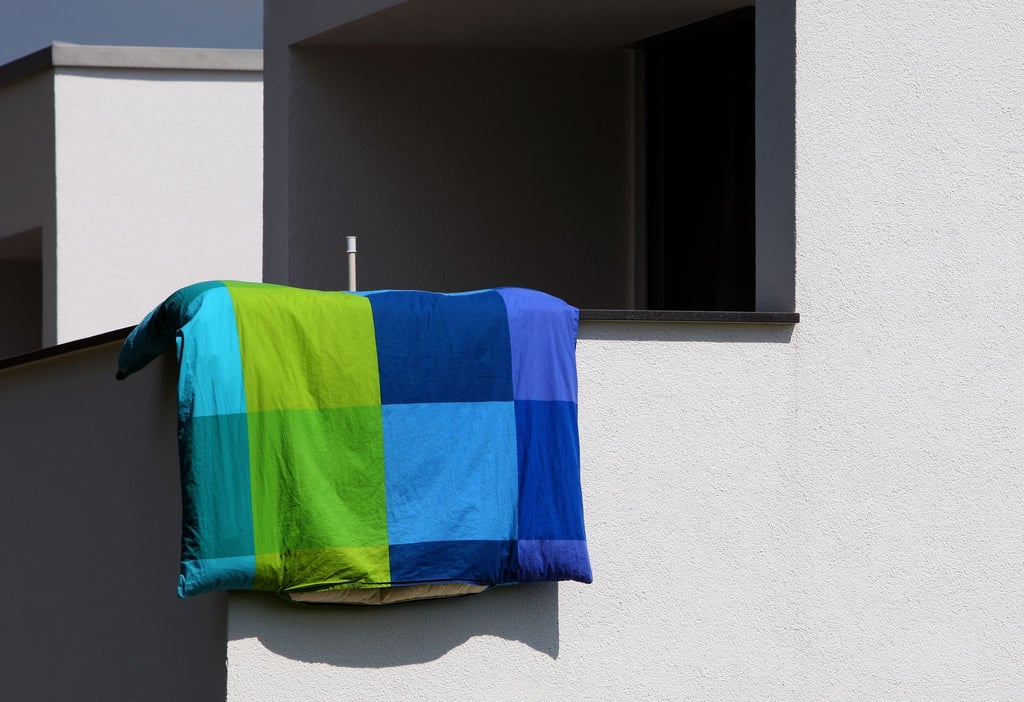 Bettwäschelüften erlaubt: Laut Landgericht Karlsruhe müssen Nachbarn das morgendliche Lüften von Bettwäsche aus dem Fenster hinnehmen, solange die Hausordnung es nicht ausdrücklich untersagt.