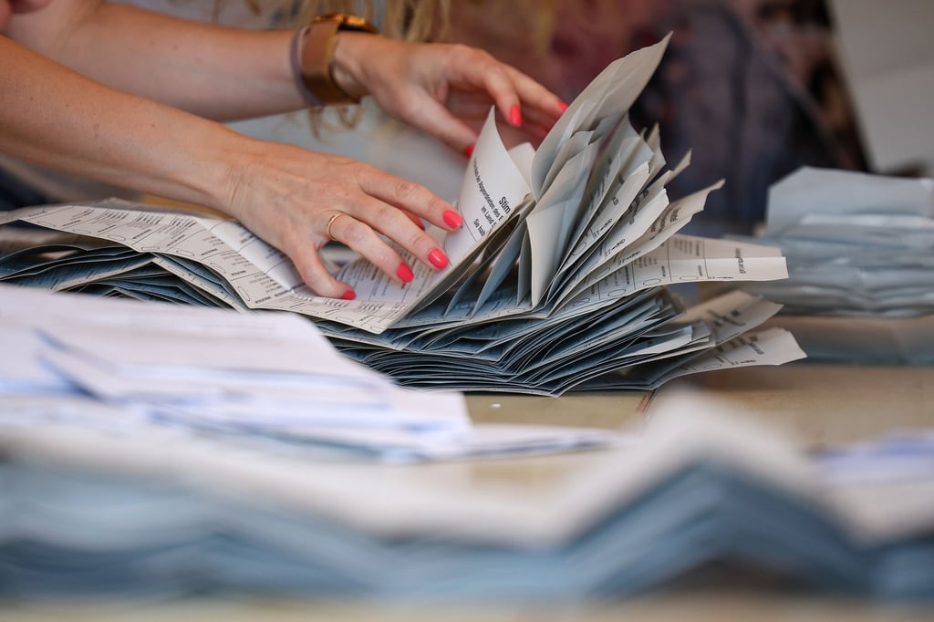 Eine Wahlhelferin legt Europawahl-Stimmzettel zur Auszählung auf einem Stapel (Archivbild)
