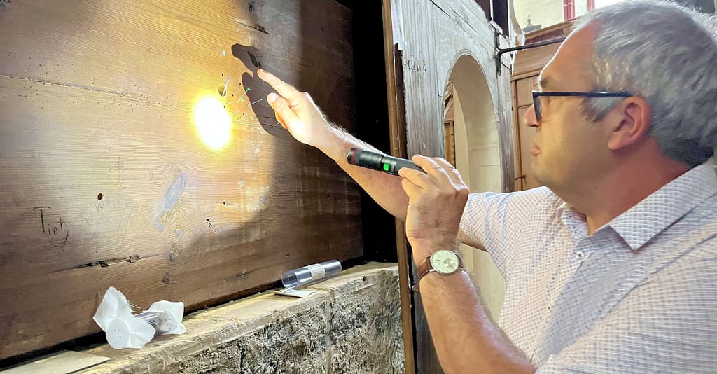 Torsten Heidecke untersucht die Fläche an der Rückseite des Altars in der Tangermünder St.-Stephanskirche. Hier wurden nach den ersten beiden Einsätzen der Schlupfwespen Stellen markiert, die eindeutig von den Wespen genutzt wurden. Deren Löcher im Holz sind wesentlich kleiner als die der Holzwürmer.