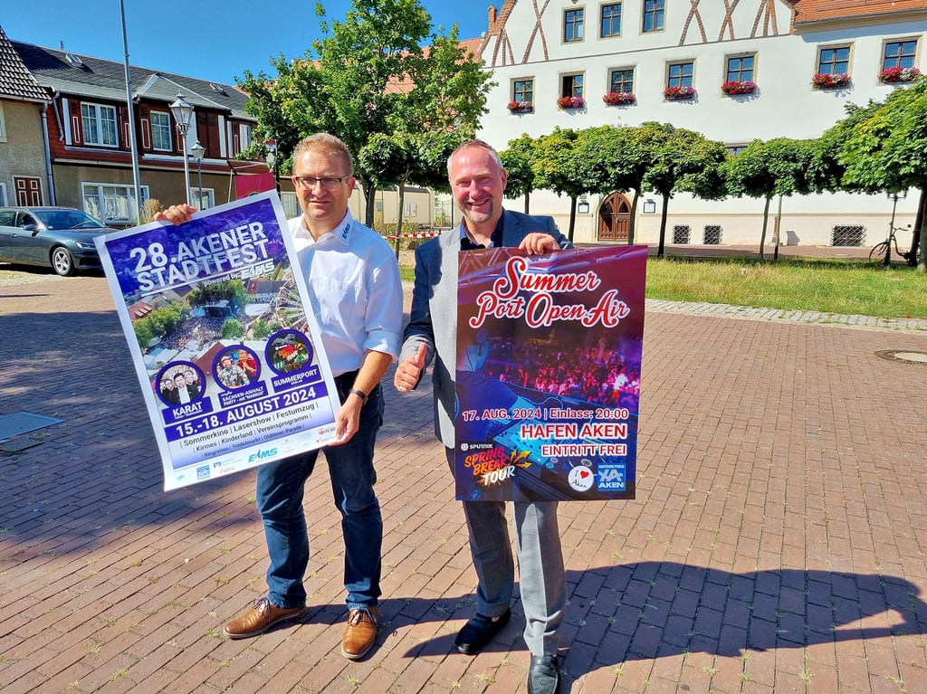 Frank Sieweck, Sprecher der EMS GmbH, und Akens Bürgermeister Jan-Hendrik Bahn (r.) präsentieren die Plakate zum Stadtfest.