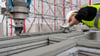 Ein Mitarbeiter eines Bauunternehmens beobachtet einen 3D-Drucker, der die nächste Schicht Beton auf Wände aufträgt. Der 3d-Druck ist am 26.5. Thema für einen Vortrag im Alten Rathaus in Magdeburg.