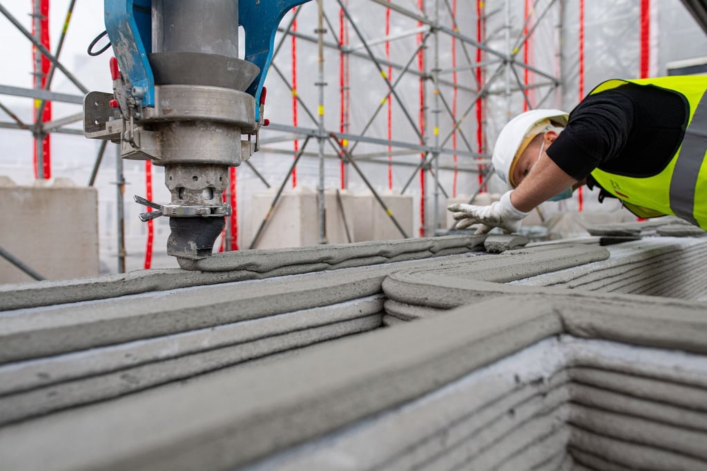 Ein Mitarbeiter eines Bauunternehmens beobachtet einen 3D-Drucker, der die nächste Schicht Beton auf Wände aufträgt. Der 3d-Druck ist am 26.5. Thema für einen Vortrag im Alten Rathaus in Magdeburg.