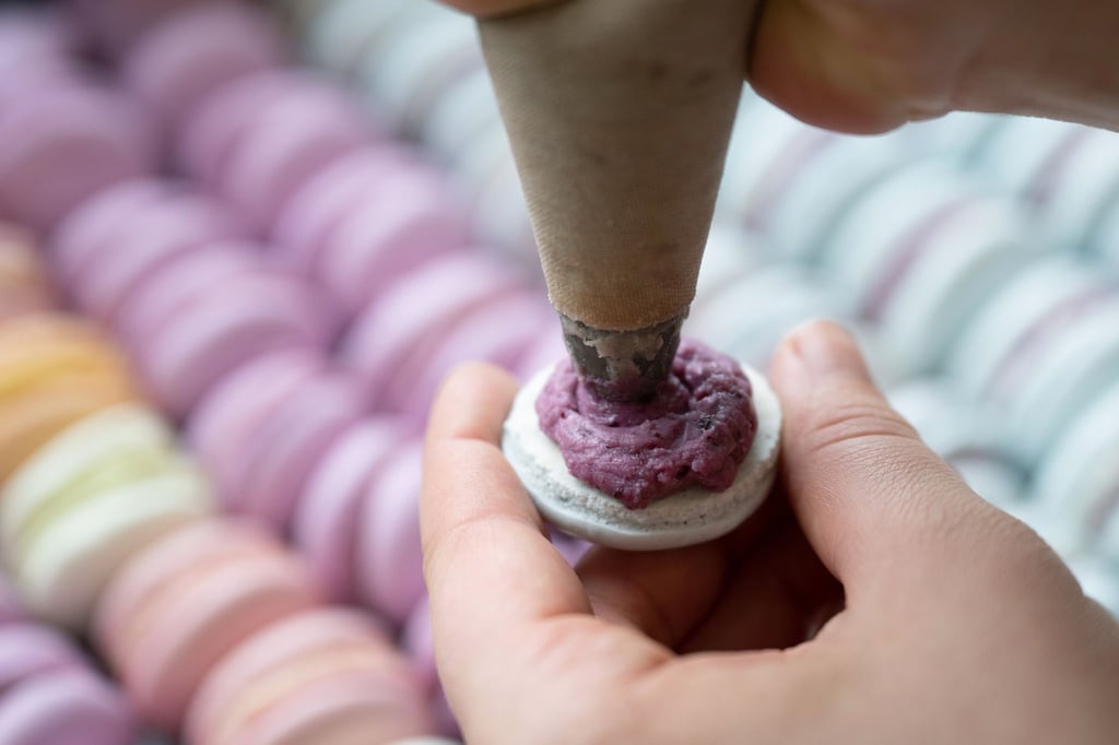 Das Baisergebäck Macaron wird in einer Bäckerei mit einer Spritztüte befüllt. (Archivbild)