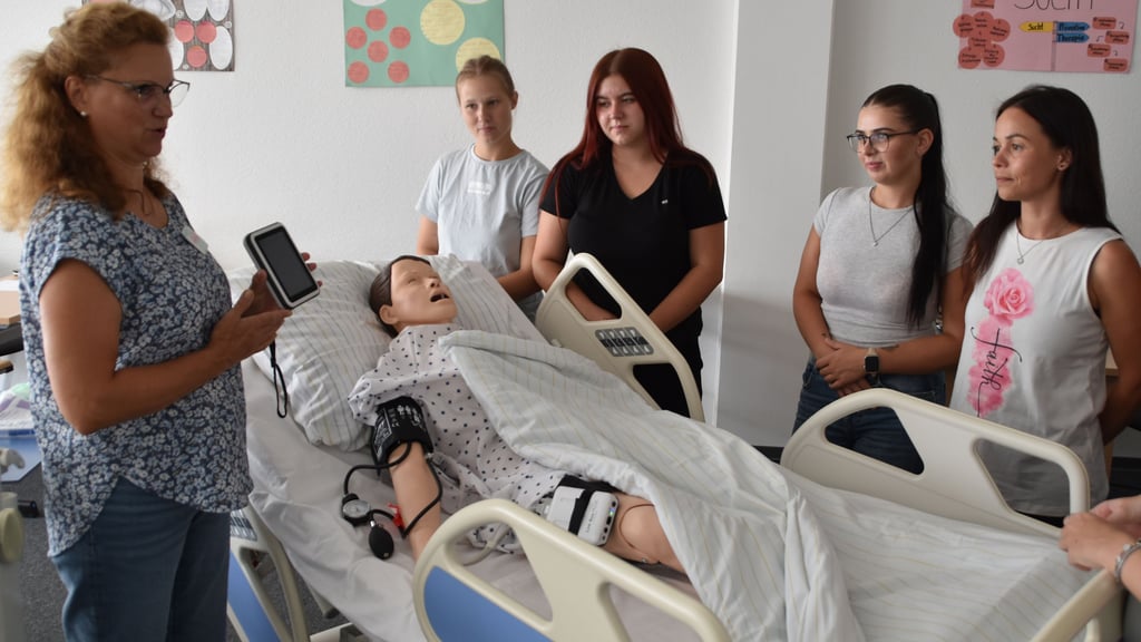 Lehrkraft Cornelia Schröder erklärt den Azubis die Funktionsweise der neuen Pflegepuppe.