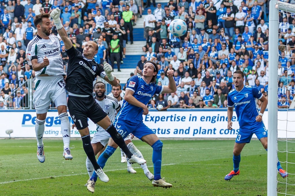 Kenan Karaman (l) springt höher als Magdeburgs Torwart Dominik Reimann und trifft.