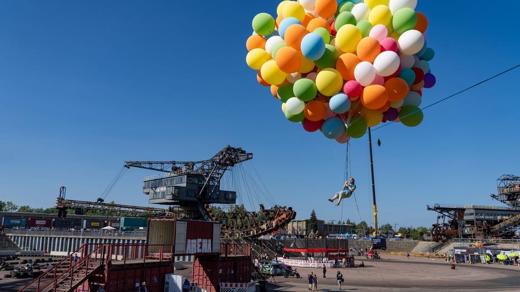 Ein Besucher vom Macher Festival 2024 der Real Life Guys steigt an Helium-Ballons in die Luft.