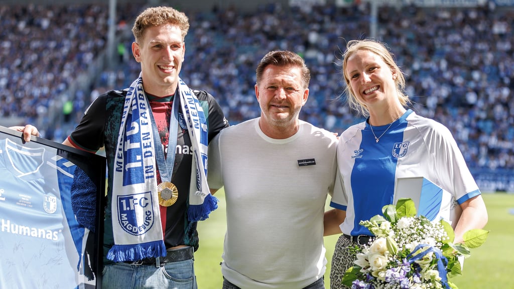 Die Olympia-Stars Lukas Märtens und Isabell Gose posieren mit FCM-Trainer Christian Titz beim Heimspiel des 1. FC Magdeburg gegen FC Schalke 04 am Sonntag.