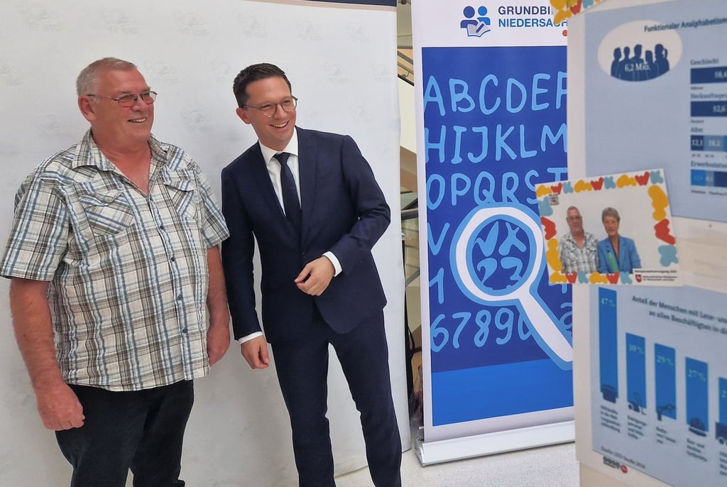 Falko Mohrs (r), Wissenschaftsminister von Niedersachsen, und der Betroffene Uwe Boldt positionieren sich vor einer Fotobox, die anlässlich des bevorstehenden Weltalphabetisierungstages im Landtag aufgestellt wurde.