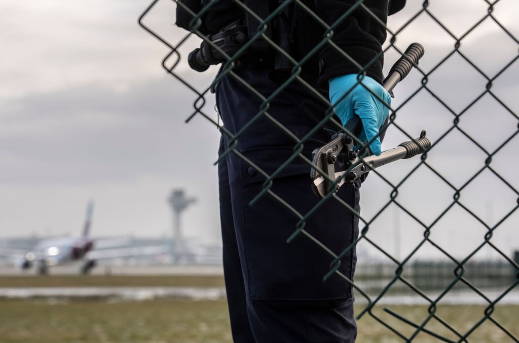 Eine Beamtin der Bundespolizei steht nach einer Protestaktion der „Letzten Generation“ im Herbst 2022 mit einem sichergestellten Bolzenschneider an einem Zaun am Flughafen BER.