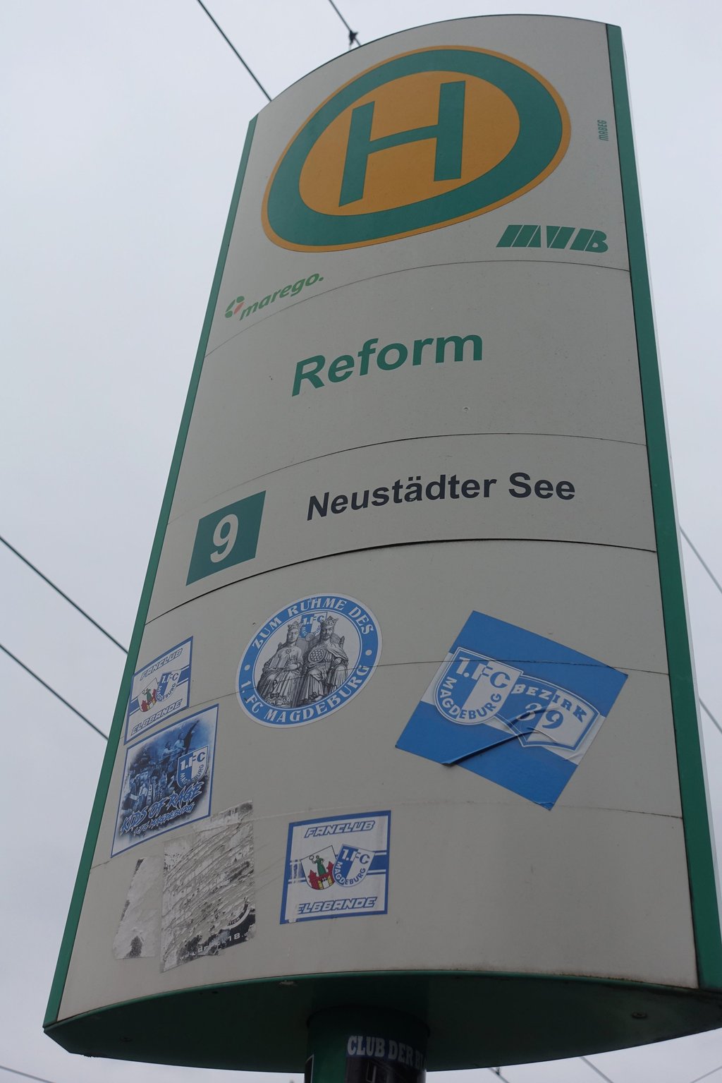 Auf dem Haltestellenschild der MVB kleben weitere blau-weiße Sticker vom 1. FC Magdeburg.