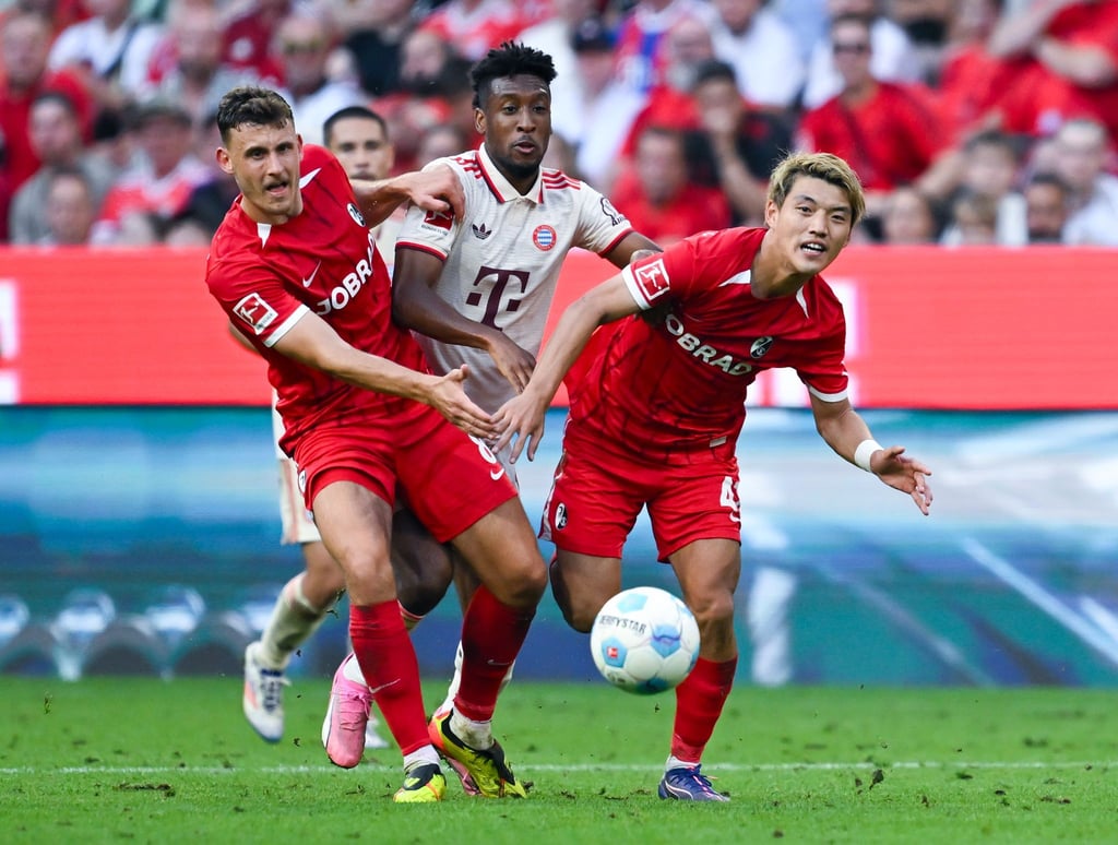 Bayerns Kingsley Coman (M) im Kampf mit zwei Freiburger Gegenspielern.