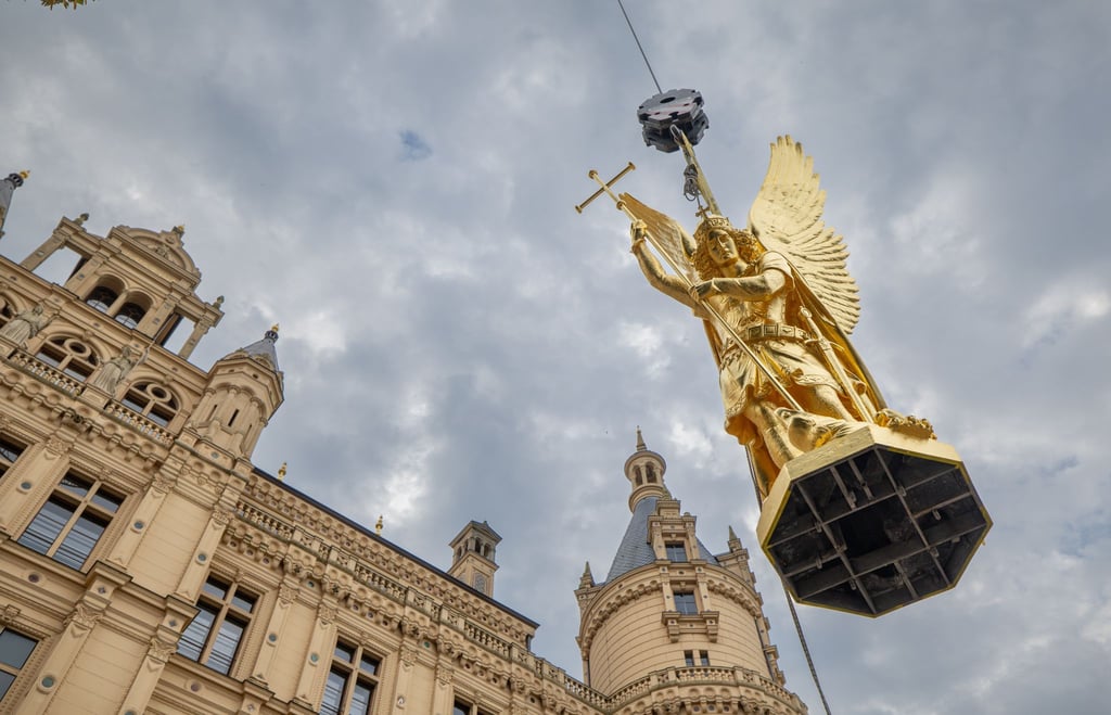 Per Kran wird der Erzengel Michael nach mehrmonatigen Sanierungsarbeiten zurück auf die Kuppel des Schweriner Schlosses befördert.