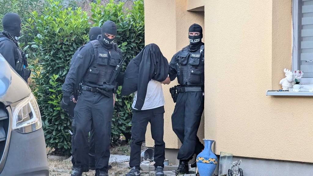 Polizeibeamte führen am Mittwoch einen Verdächtigen bei einer Schleuserrazzia in Jena ab. Auch in Zeitz kam es zu einer Durchsuchung.