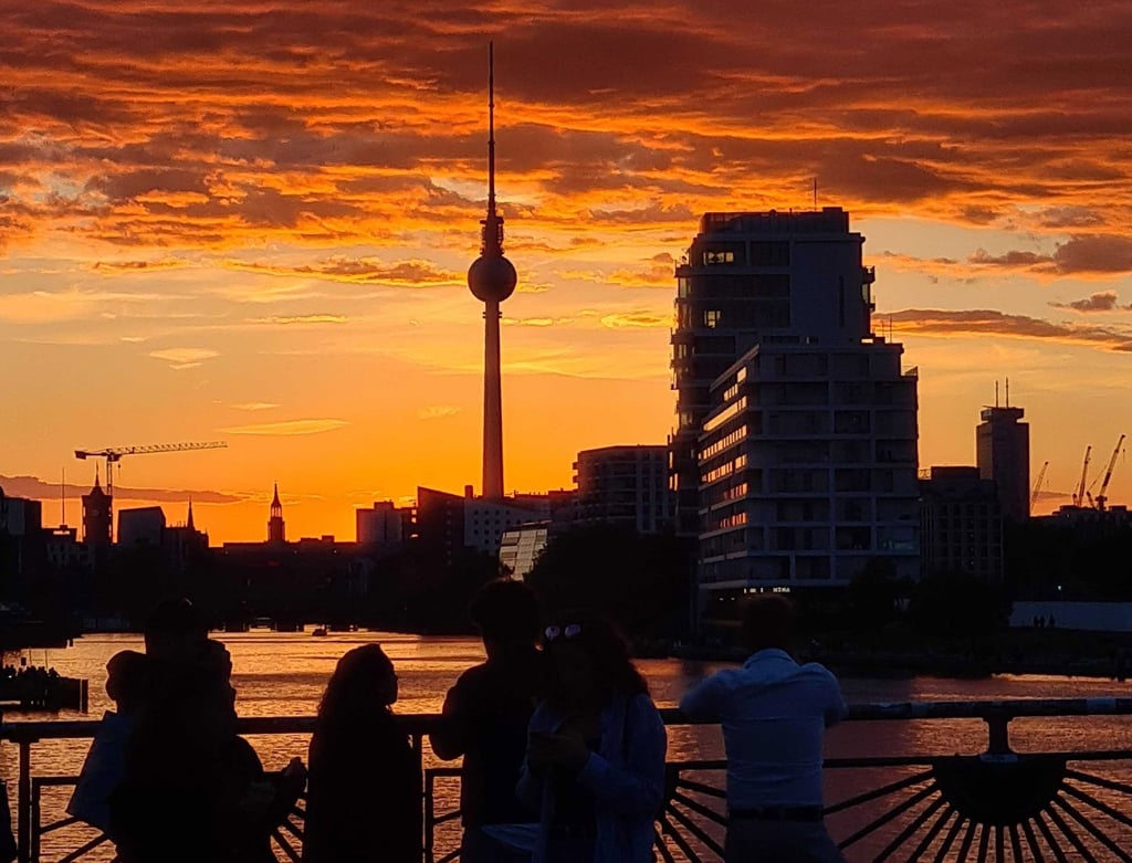 Menschen betrachten auf der Oberbaumbrücke den Sonnenuntergang über der Spree. Im Hintergrund ist der Fernsehturm zu sehen. (Archivbild)