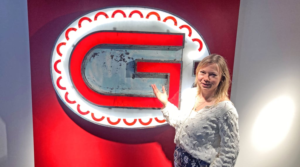 Kuratorin Anne-Christin Bielig steht vor dem Signet des Gastronoms.