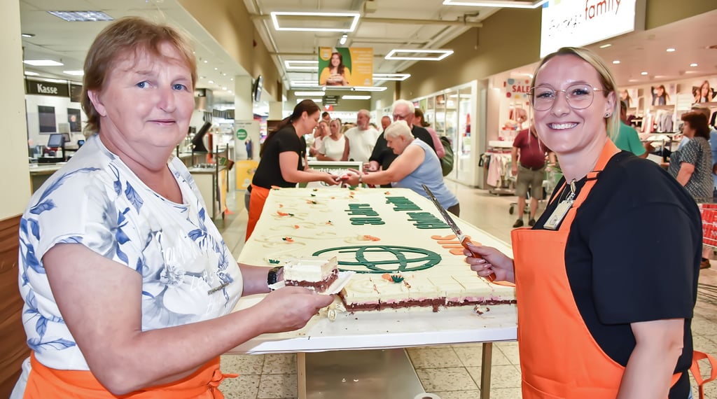 Jetzt geht es Los: Kathrin Böhmert (links) und Susan Thomas vom Globus-Team schneiden die Buttercremetorte an. Sie ist riesig groß, misst ein mal drei Meter. Trotzdem war innerhalb einer halben Stunde bereits ein Drittel verkauft.