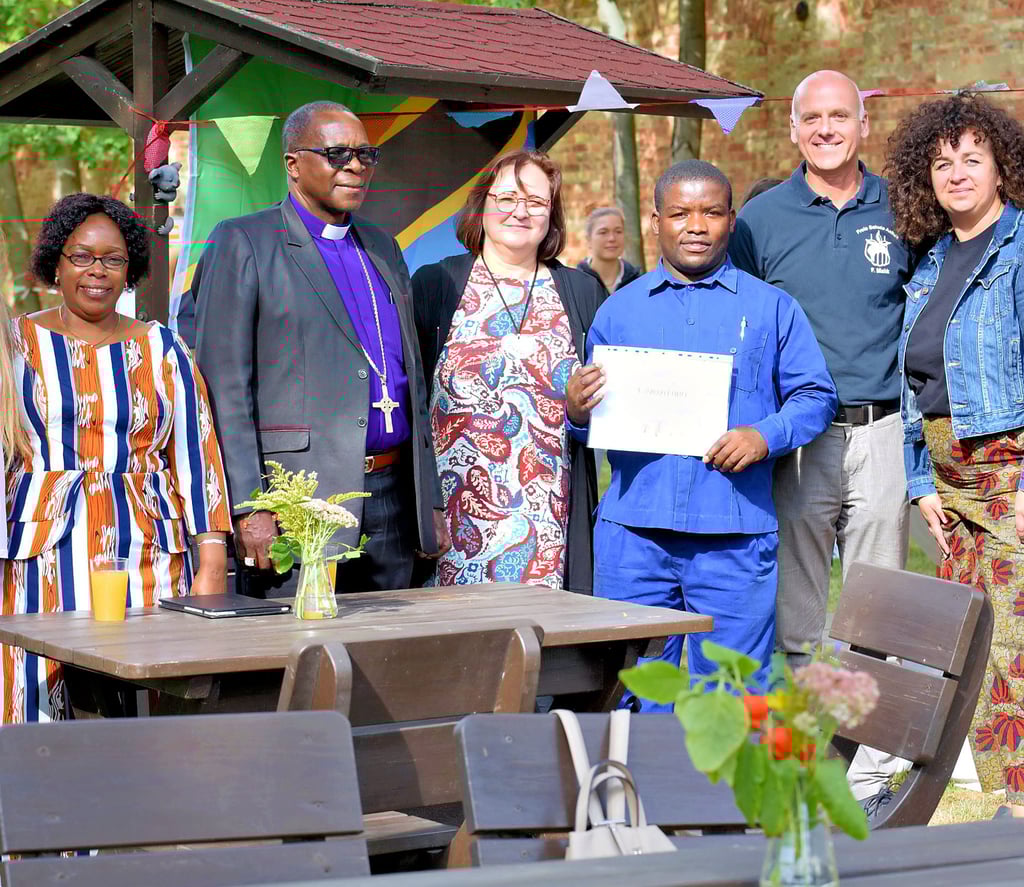 Esther Mponda und ihr Mann, Bischof Antony Kipangula, Heike Makk, Schulleiter Alphonce Ngwembele, sowie Ferenc Makk und Juliane Löbe bei der Eröffnung des Festes (v. l.). Ngewembele hält den Gutschein für die neuen Stühle, die für das Computerkabinett der Schule in Tansania gedacht sind.