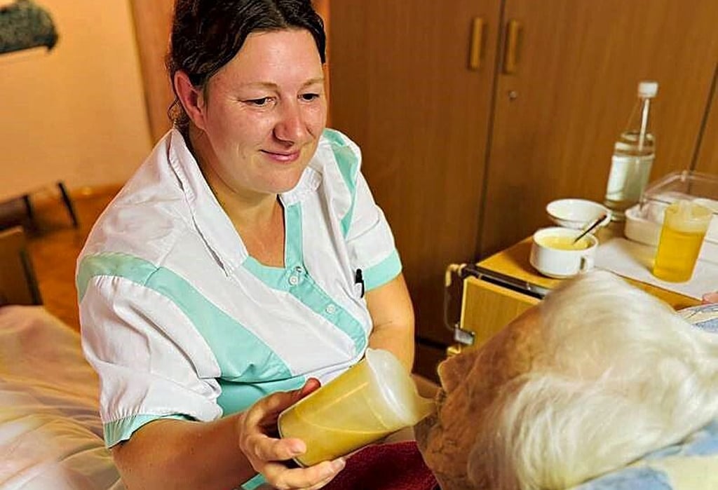 Stephanie Schulze, Auszubildende zur Pflegehelferin, hilft einer Bewohnerin beim Trinken.