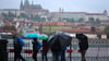 Menschen spazieren im Regen an der Moldau in Prag.