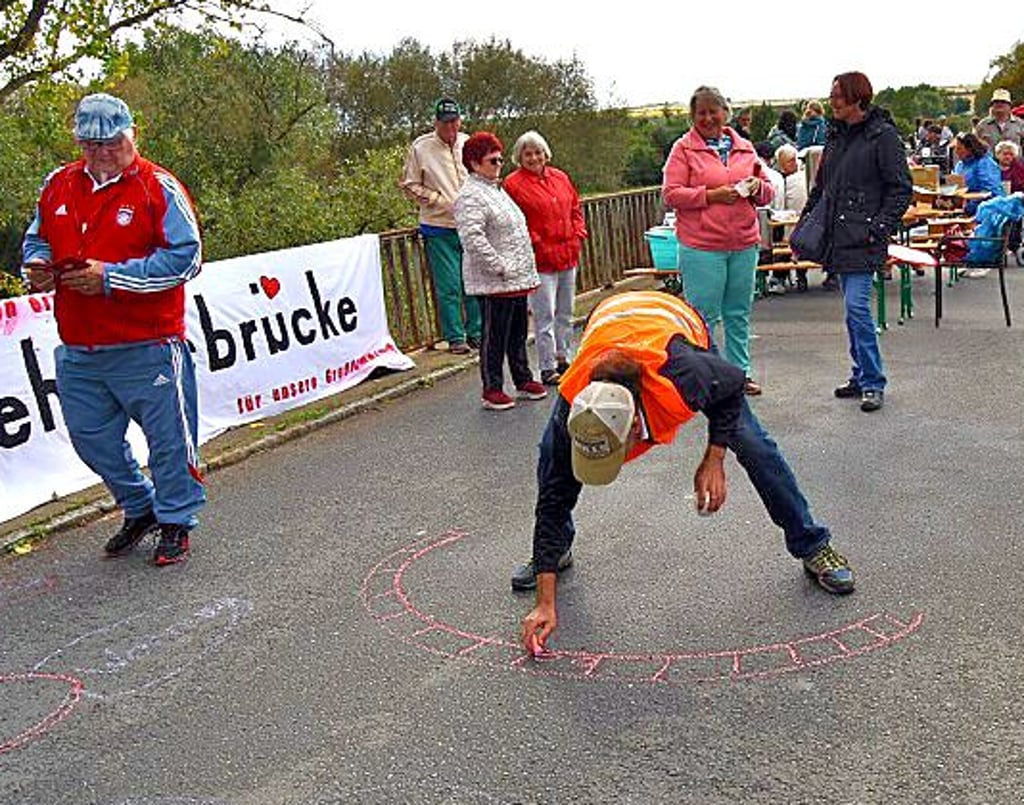 Iven Jede von der Bürgerinitiative malt symbolisch eine Behelfsbrücke.