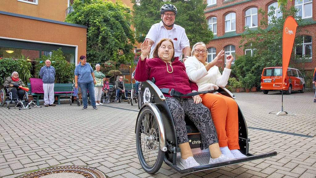 Margrit Robusch und Lisa Steffen werden von Rolf Kohlmeyer vom ADFC in der Fahrrad-Rikscha chauffiert und haben sichtlich Spaß dabei.