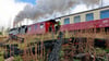 Eine Dampflok der Harzer Schmalspurbahnen GmbH fährt auf dem Weg zum Brocken an verkohlten Baumstämmen entlang. 