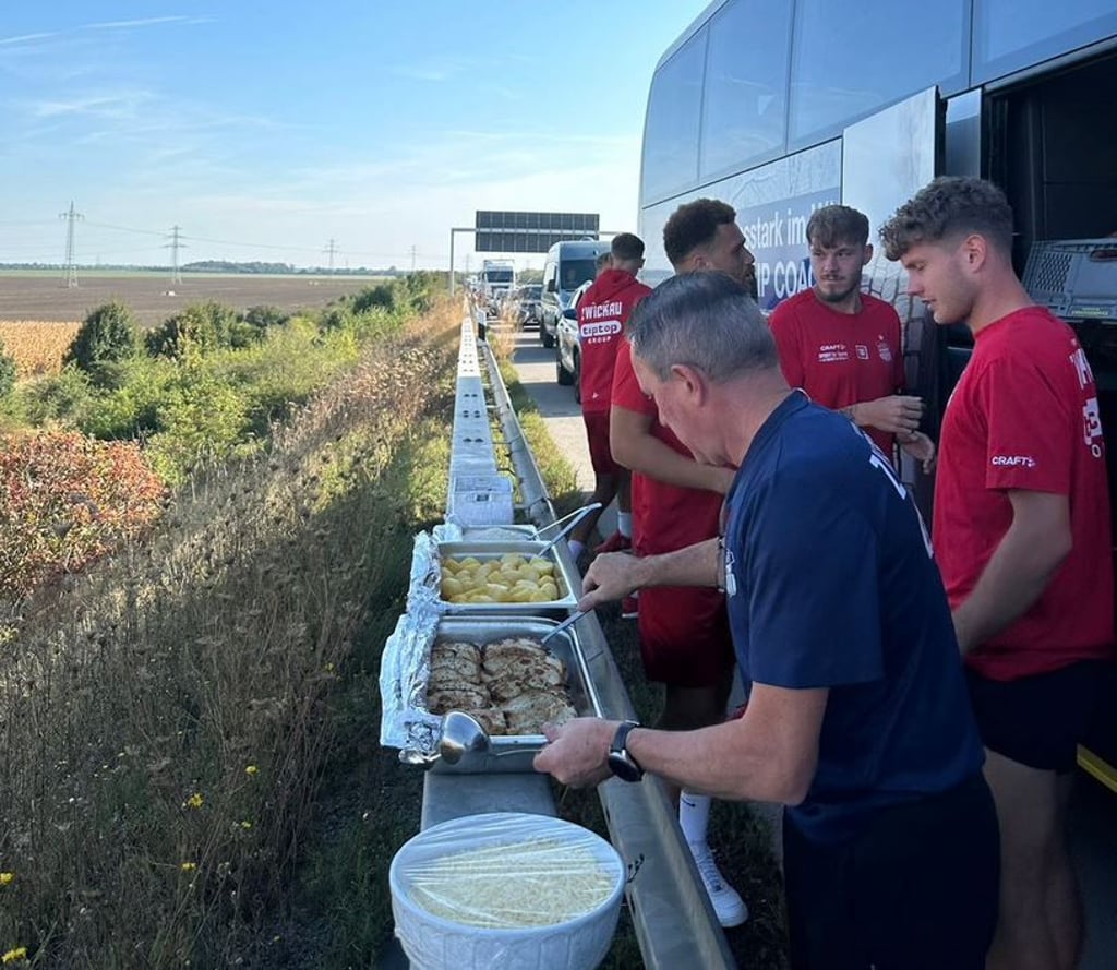 Die Spieler des FSV Zwickau lassen sich ihr Essen an der Leitplanke der A9 servieren.