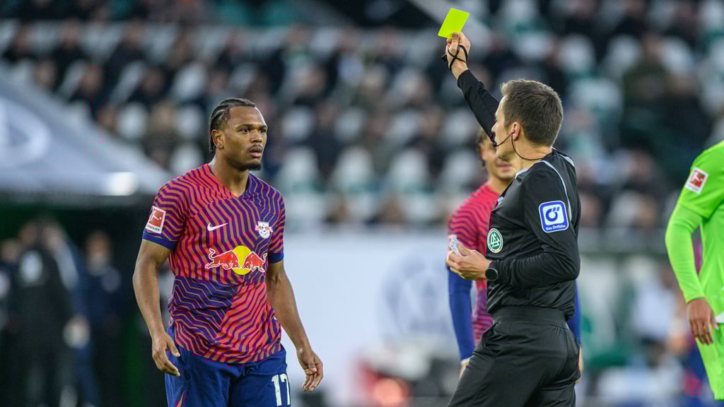 Schiedsrichter Robert Hartmann zeigt Lois Openda (l.) die Gelbe Karte.
