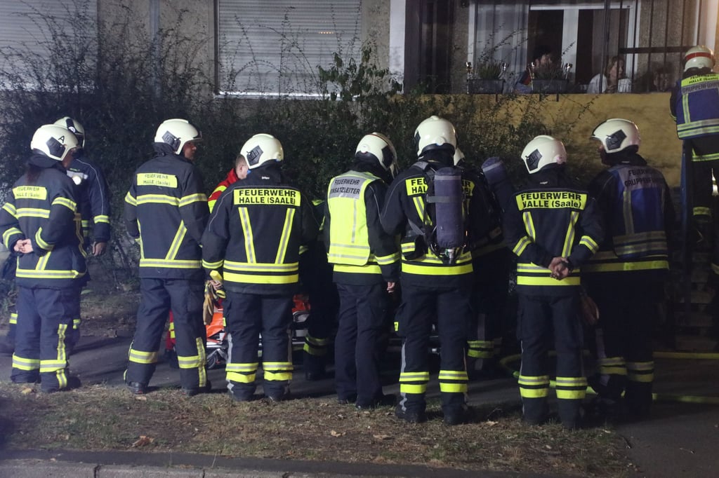Brandeinsatz in Halle: Die gerettete Person wird von Feuerwehrleuten abgeschirmt.