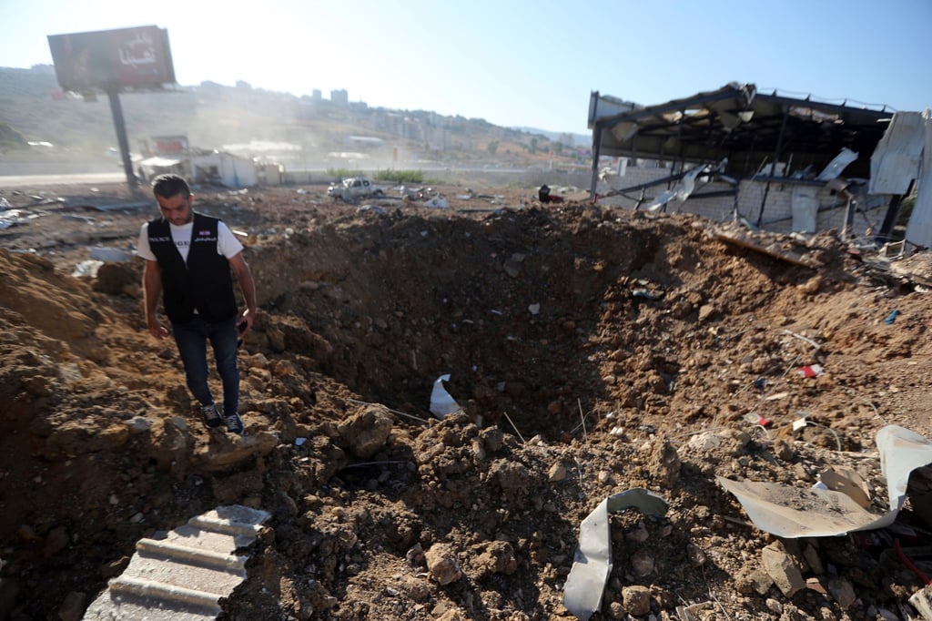Ein libanesischer Polizist steht in der Nähe eines Kraters nach einem israelischen Luftangriff auf einen Hangar im Südlibanon.