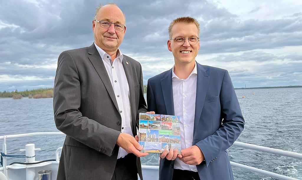 Herausgeber Matthias Haak (r.) übergibt das Heimat-Jahrbuch des Saalekreises an Landrat Hartmut Handschak.
