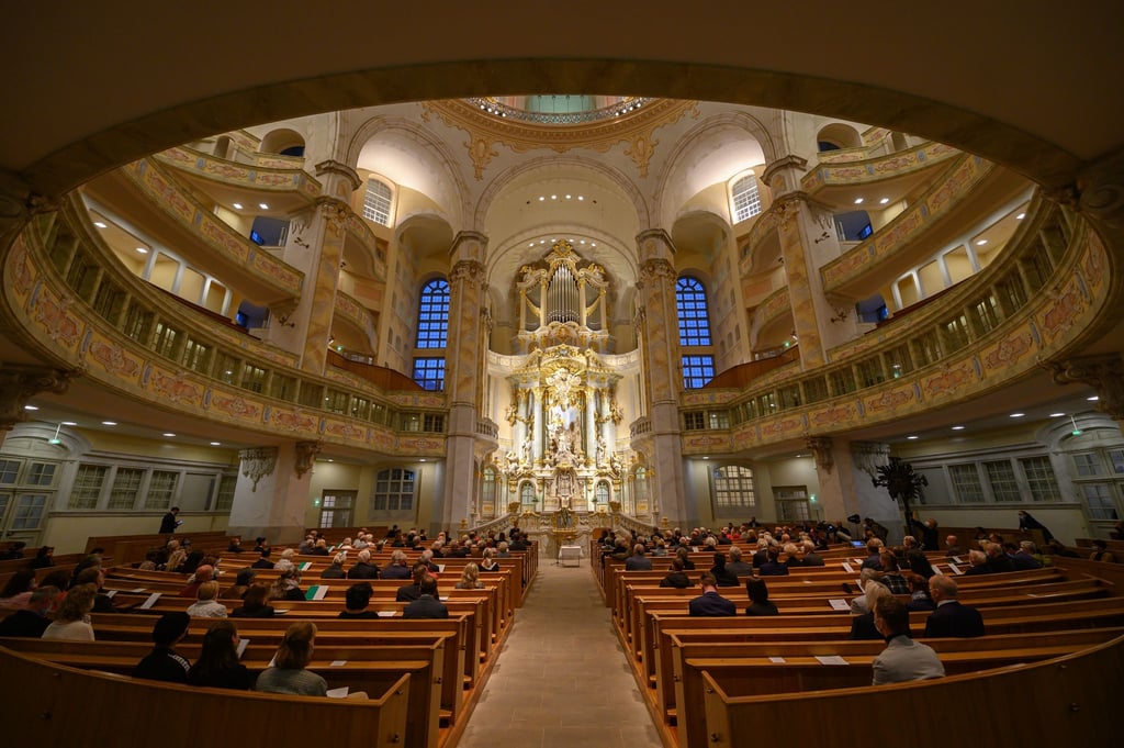 Gäste sitzen im Innenraum der Dresdner Frauenkirche unter der Sandsteinkuppel mit Blick auf den Altarraum (Archivbild).