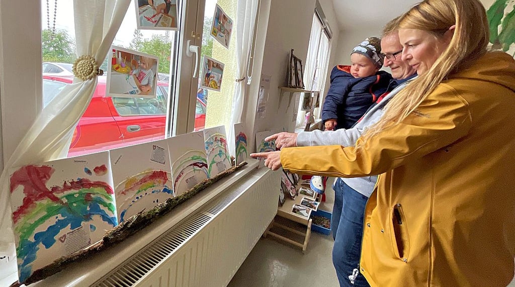 Cora und Ulrich Simon (von rechts) schauen sich mit Lew (2) die Regenbogen-Kunstwerke der kleinen Gruppe an.
