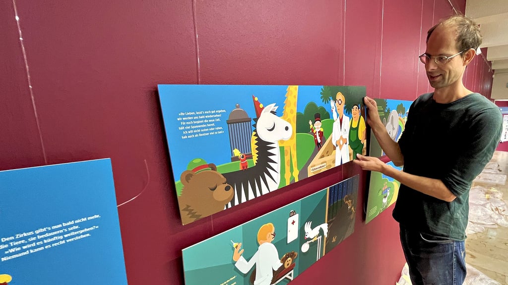 Galerie-Mitarbeiter Sebastian Schulze hängt die letzten Illustrationen von Claudia Opitz und Sebastian Köpcke auf.