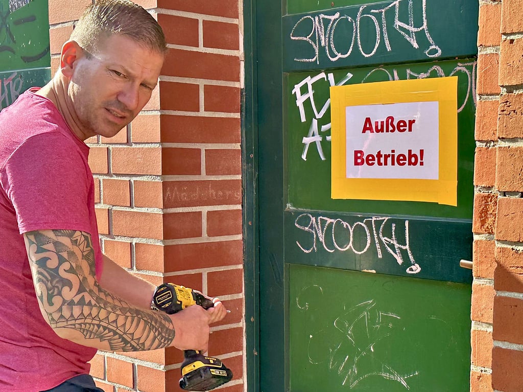 Stadt-Mitarbeiter Marc Sommer sichert die Tür der Stadttoilette in der Schartauer Straße in Burg nach einer Beschädigung.